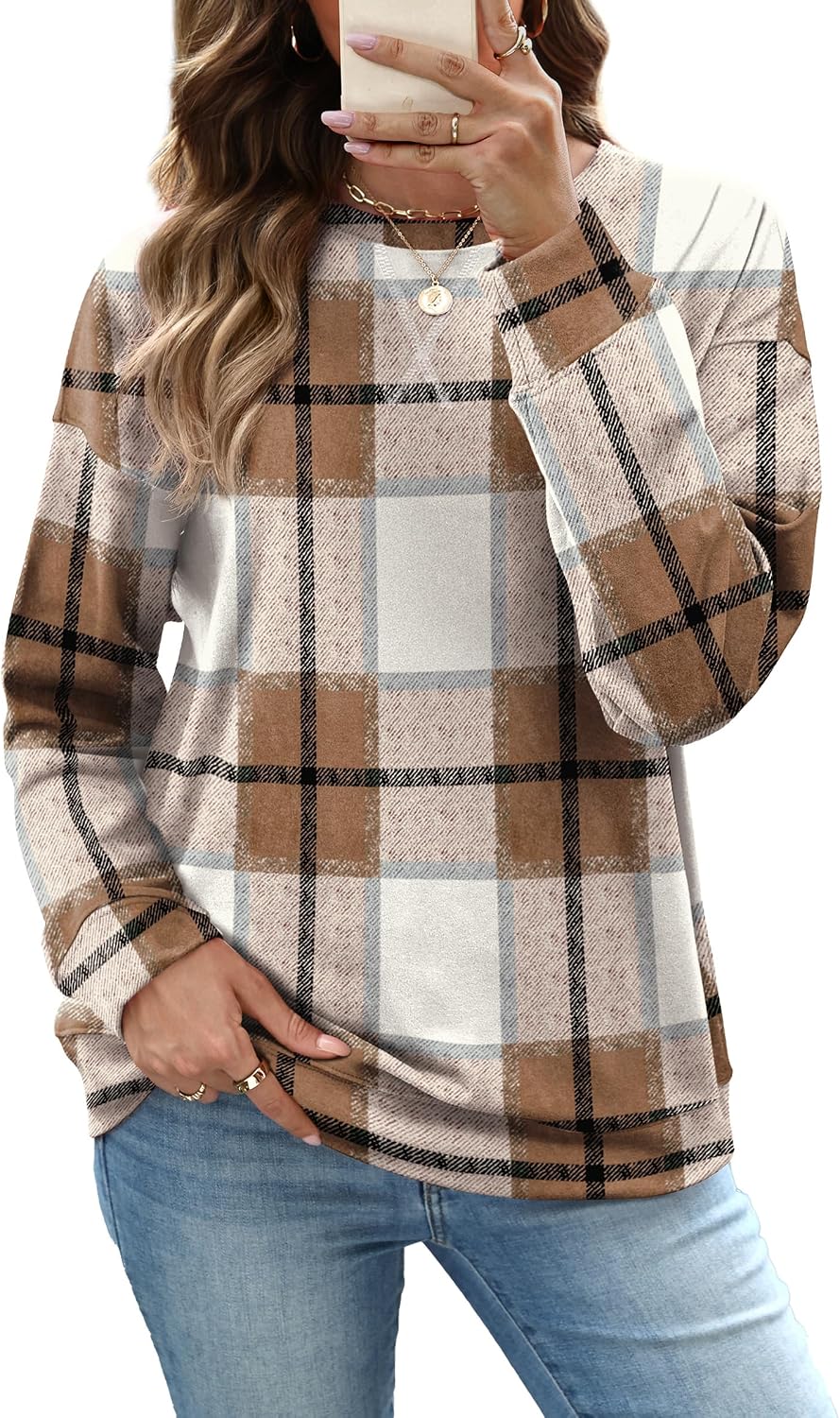 Model wearing a beige and brown plaid crewneck sweatshirt with light-wash jeans